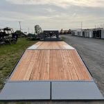 a bwise trailer with a wooden deck is parked on the side of the road .