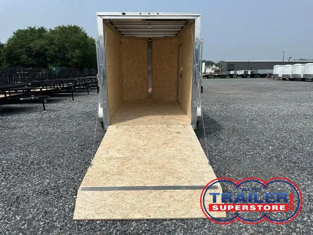 a trailer with the door open is parked in a gravel lot .