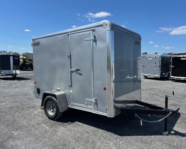 a gray trailer is parked in a gravel lot