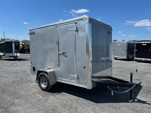 a gray trailer is parked in a gravel lot