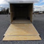 a trailer with a wooden floor is sitting in a gravel lot .