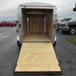 a used trailer with a wooden floor is parked in a parking lot .