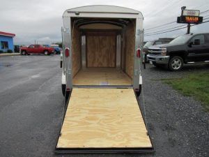 a used trailer with a wooden floor is parked in a parking lot .