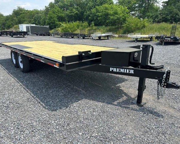 a trailer with a wooden deck is parked in a gravel lot .