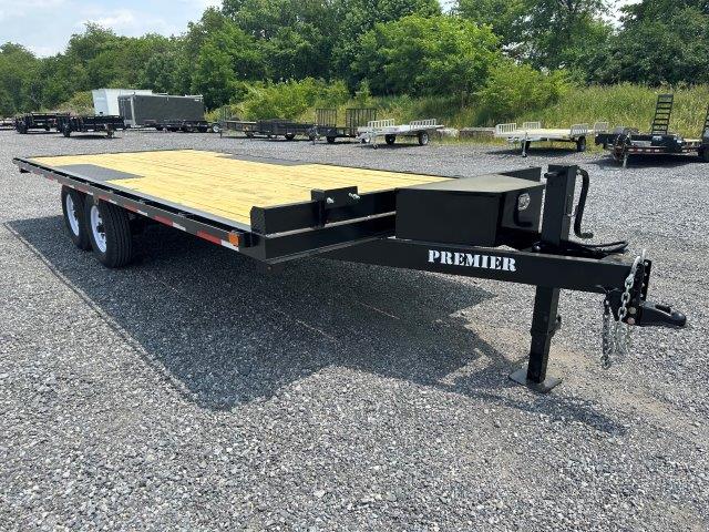 a trailer with a wooden deck is parked in a gravel lot .
