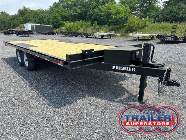 a trailer with a wooden deck is parked in a gravel lot .