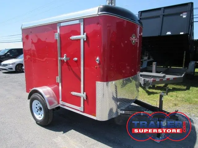 a red trailer is parked on the side of the road next to a dump trailer