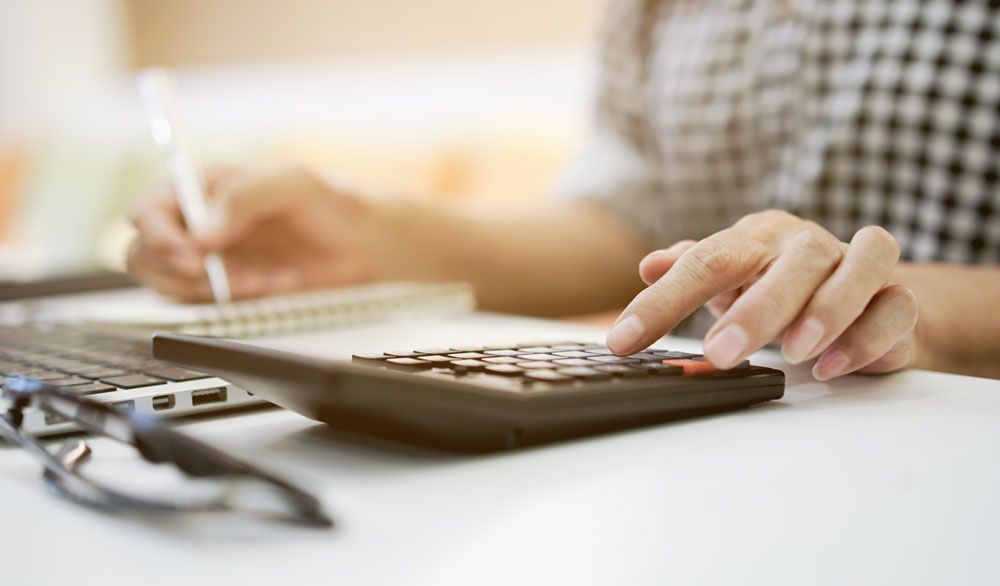 a person is using a calculator and writing in a notebook