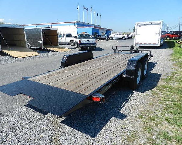 a trailer with a wooden deck is parked in a gravel lot