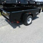 a black trailer is parked on the side of the road .