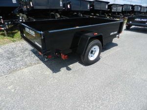 a black trailer is parked on the side of the road .