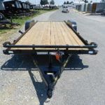 a trailer with a wooden deck is parked on the side of the road .