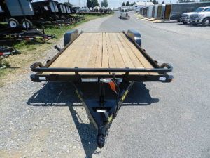 a trailer with a wooden deck is parked on the side of the road .