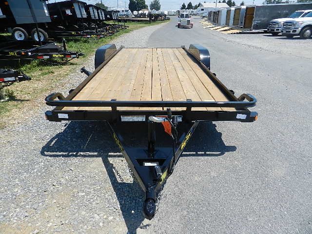 a trailer with a wooden deck is parked on the side of the road .