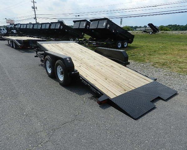 a black trailer with a wooden deck is parked on the side of the road .
