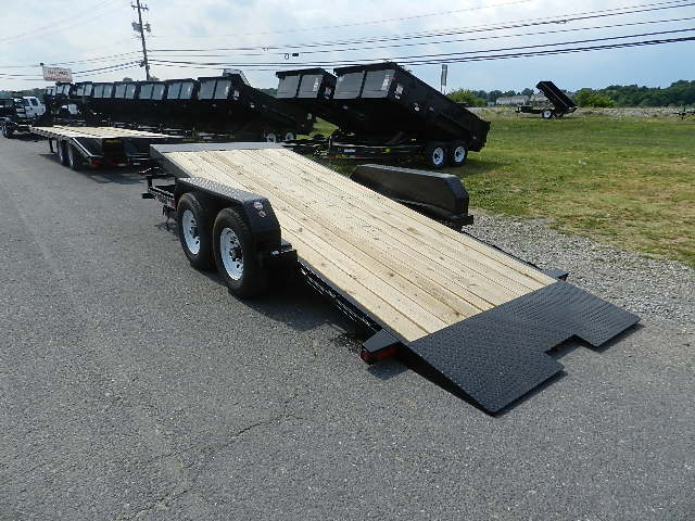 a black trailer with a wooden deck is parked on the side of the road .