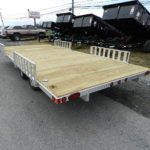 a trailer with a wooden deck is parked on the side of the road .