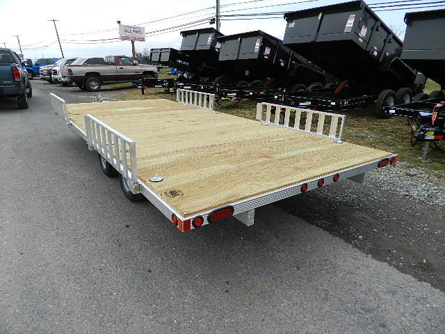 a trailer with a wooden deck is parked on the side of the road .