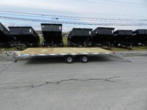 a Deckover trailer parked next to a row of dump trailers