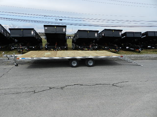 a Deckover trailer parked next to a row of dump trailers