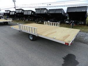 a trailer with a wooden deck is parked on the side of the road .
