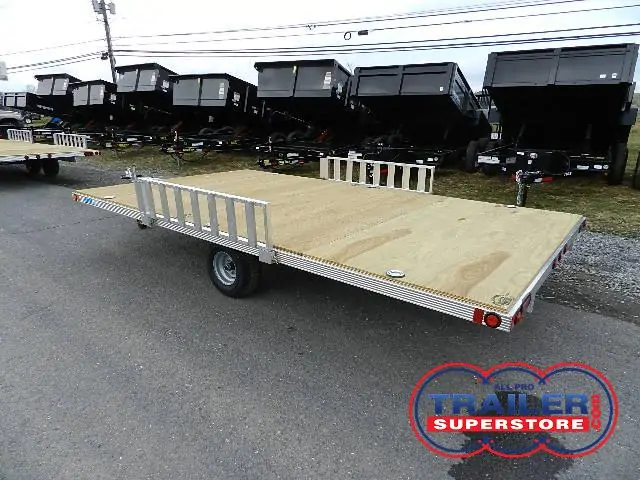 a trailer with a wooden deck is parked on the side of the road .