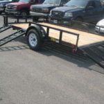 a trailer is parked next to a row of cars .