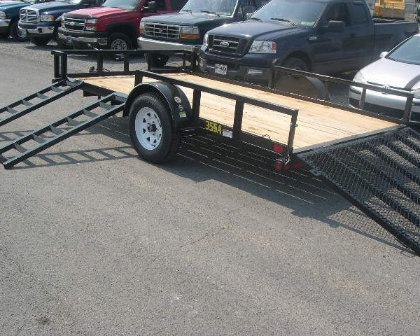a trailer is parked next to a row of cars .
