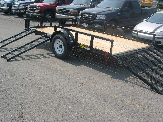 a trailer is parked next to a row of cars .