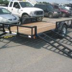 a Big Tex trailer with ramps attached to it parked in a parking lot