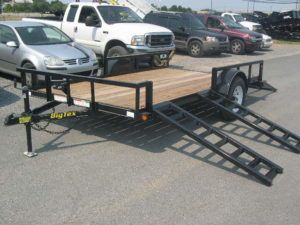 a Big Tex trailer with ramps attached to it parked in a parking lot