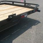 a trailer with a wooden deck is parked on the side of the road .
