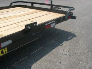 a trailer with a wooden deck is parked on the side of the road .