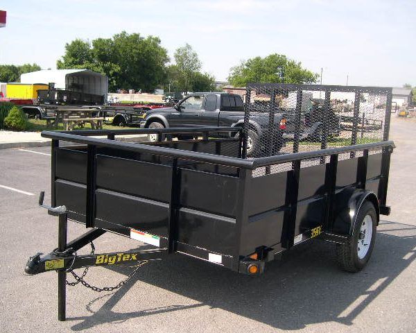 a black trailer is parked in a parking lot next to a truck .