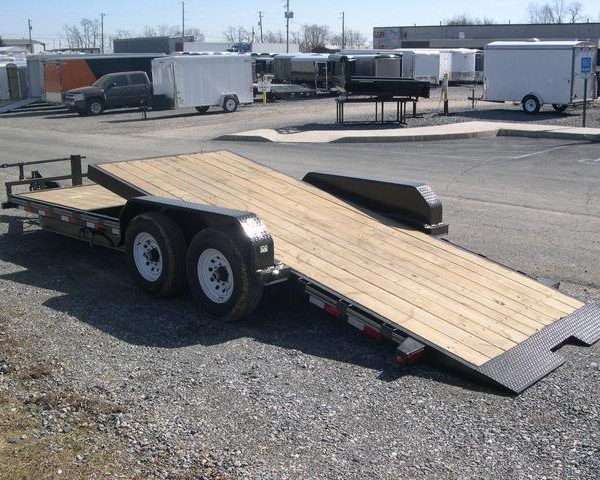 a flatbed trailer is parked in a gravel lot