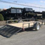 a trailer is parked on the side of the road next to a dump truck .