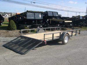 a trailer is parked on the side of the road next to a dump truck .