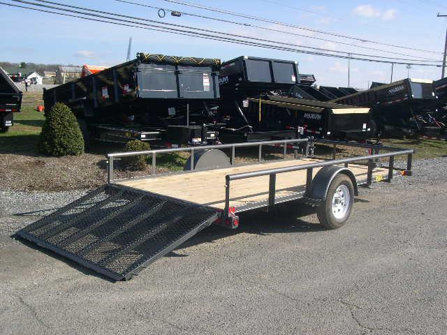 a trailer is parked on the side of the road next to a dump truck .