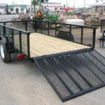 a Carry On trailer with a ramp attached to it parked on the side of the road