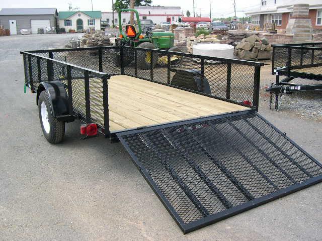 a Carry On trailer with a ramp attached to it parked on the side of the road