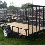 a trailer with a wooden deck is parked in the grass