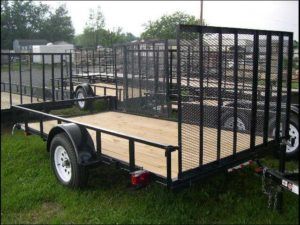 a trailer with a wooden deck is parked in the grass