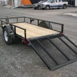 a Big Tex trailer with a ramp attached to it parked in a gravel lot