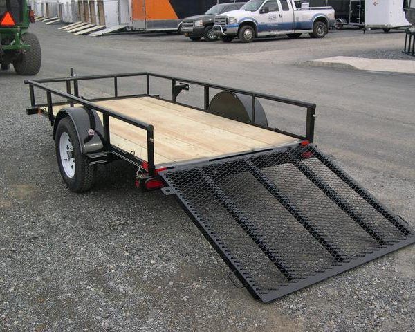 a Big Tex trailer with a ramp attached to it parked in a gravel lot