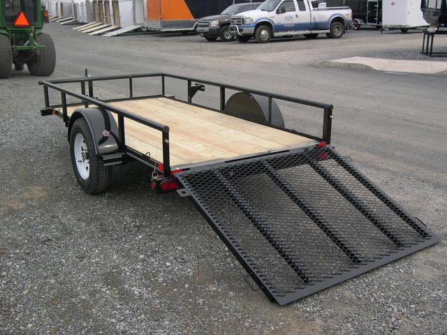 a Big Tex trailer with a ramp attached to it parked in a gravel lot