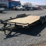 a Big Tex trailer parked in a gravel lot in front of a building