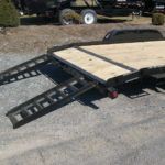 a black car trailer with slide in ramps attached to it