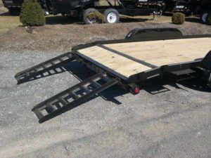 a black car trailer with slide in ramps attached to it