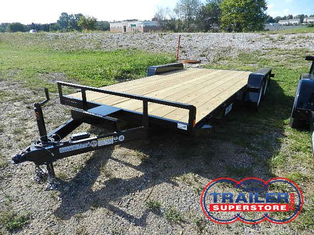 a trailer with a wooden deck is parked in a grassy field .