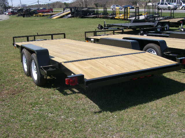 a black trailer with a wooden deck parked in a grassy field
